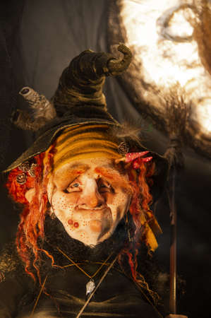 Halloween decorations, Spooky, evil, creepy, horrible, terrifying, good witch with freckles, warts, mushrooms, red hair and a broom in an old witch hat and rags in the moonlightの写真素材