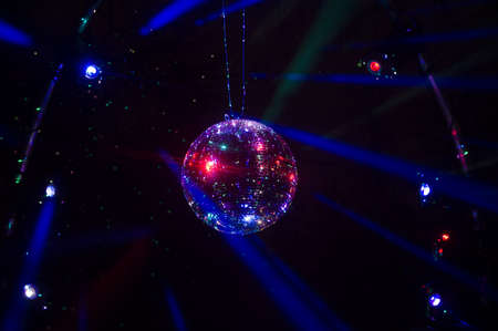 Mirrored Disco Ball and bright beams at the night party. Party attribute reflects Lazer lights. Abstract background with defocused rays. Night club atmosphere. Installation at Vilnius light festivalの写真素材