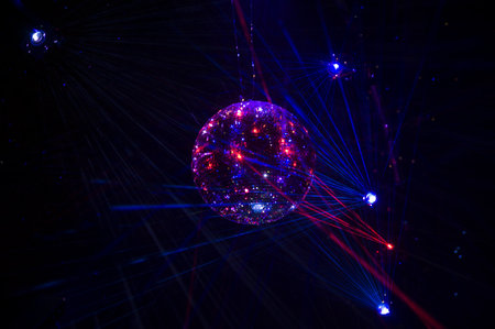 Mirrored Disco Ball and bright beams at the night party. Party attribute reflects Lazer lights. Abstract background with defocused rays. Night club atmosphere. Installation at Vilnius light festivalの写真素材