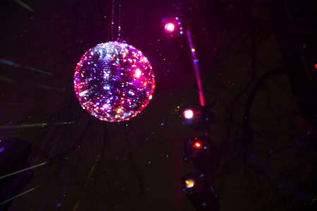 Mirrored Disco Ball and bright beams at the night party. Party attribute reflects Lazer lights. Abstract background with defocused rays. Night club atmosphere. Installation at Vilnius light festivalの写真素材