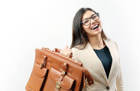 Toothy dark haired lady in glasses holding light brown leather handbag against isolated white backgroundの写真素材