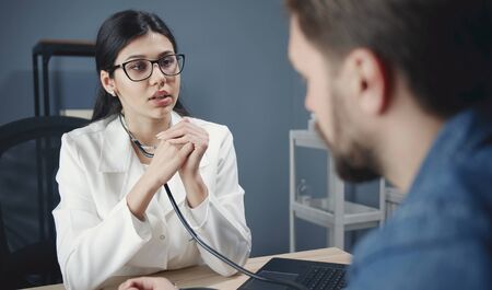 Young woman doctor working with male patient, talking, asking figuring out what concerns himの写真素材