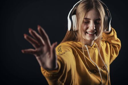 Young woman with headset dancing listening to music with closed eyes, unfocused hand foregroundの写真素材