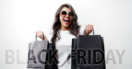 Half-length of young positive brown-haired female holding some black shopping bags in two handsの写真素材