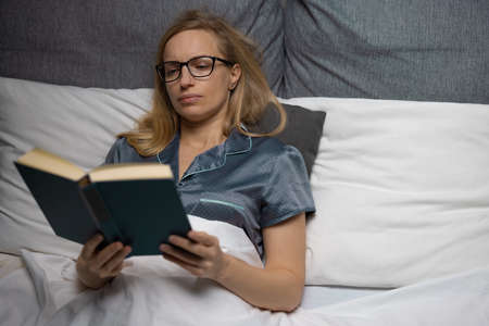 Woman reading book before sleepの写真素材