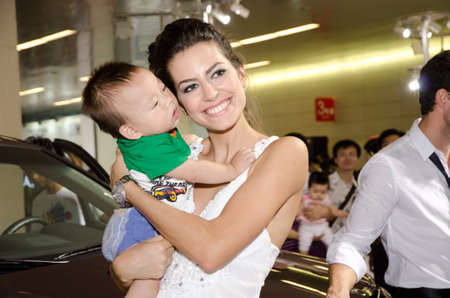 GUANGZHOU, CHINA - OCT 02: Fashion model with baby at the Guangzhou daily Baiyun international automobile exhibition. on October 02, 2011 in Guangzhou China.のeditorial素材