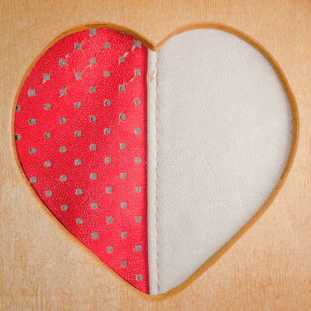 wood heart shape frame with red leather backgroundの写真素材