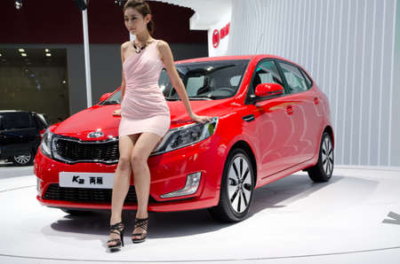 GUANGZHOU, CHINA - NOV 26: unidentified model with KIA K2 car at the 9th China international automobile exhibition. on November 26, 2011 in Guangzhou China.のeditorial素材
