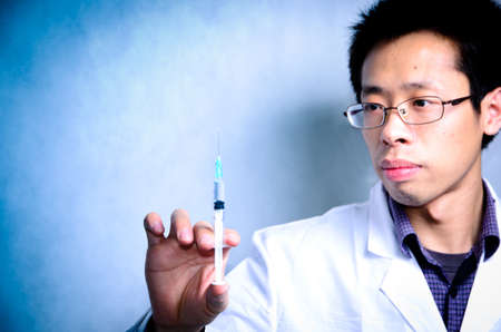 asian men doctor with medical syringe in handの写真素材