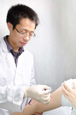 asian doctor injecting vaccination with patient handの写真素材