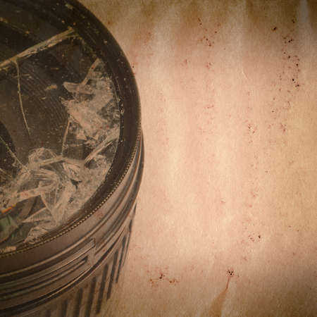 Broken DSLR camera lens on old grunge paper texture backgroundの写真素材