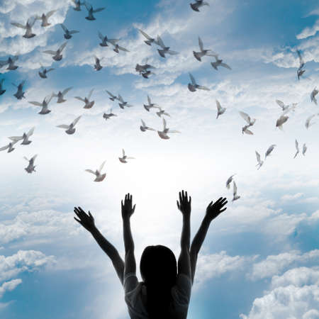 Silhouette of girl and flying dove on sky background, freedom and peace conceptの写真素材