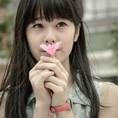 Asian Chinese girl with flower in hand on spring nature dayの写真素材