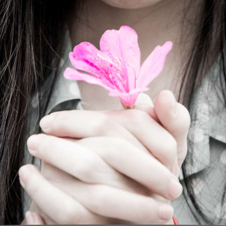 Asian Chinese girl with flower in hand on spring nature dayの写真素材