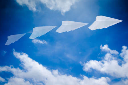 paper plane flying in blue skyの写真素材