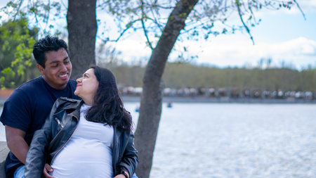 Young pregnant couple in the park at the day time. Concept of pregnancy and maternity.の写真素材