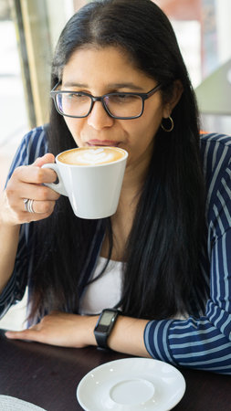 Young woman drinking coffee in a cafe. Close up portrait.の写真素材