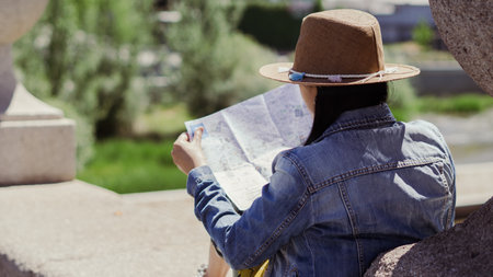 Young tourist sitting on a bridge relaxing on a summer afternoon with map in hand.