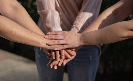 three friends joining hands and sharing on a summer afternoon with the sun shining on their radiant