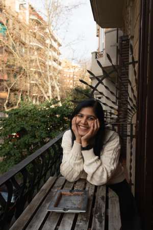 A woman is sitting on a bench outside with a book in front of her. She is smiling and looking at the cameraの写真素材