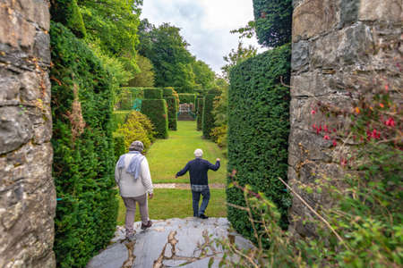 Plas Brondanew, Gwynedd, North Wales, United Kingdom - July 21, 2018: Two visitors, man and woman going down steps in the topiary garden of Plas Brondanw, Gwynedd, North Walesのeditorial素材