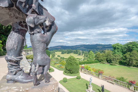 Powis Castle, Powys, Wales, United Kingdom - July 22, 2018: Bronze dog at the feet of his master overlooking the estate and the rest of the landscape, Powis Castle, Wales, Powys, Walesのeditorial素材
