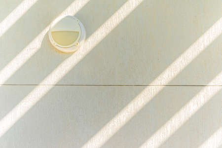Outdoor light fixture on textured white wall and rays of sunlight, Umm Al Emarat Park, Abu Dhabi, United Arab Emiratesの写真素材