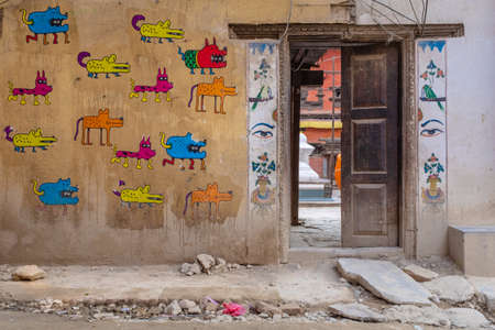 Lalitpur, Patan, Nepal - April  3, 2019: An anonymous contemporary mural showing dogs near a court entrance with traditional drawings,  taken during a partly cloudy morning in the historical district of Patanのeditorial素材