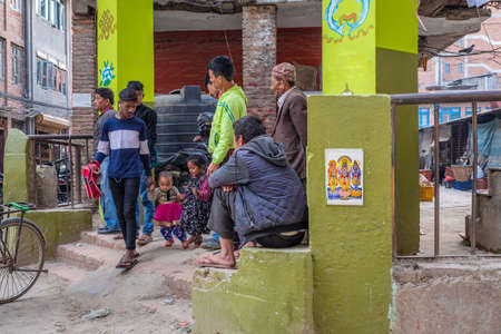Lalitpur, Patan, Nepal - April  3, 2019: A nepalese dad with its two kids and other men near a school, taken during a partly cloudy morning in the historical district of Patanのeditorial素材