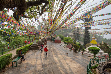 Kathmandu, Nepal - March 30, 2019:  Few visitors and lines of prayer flags forming convergent lines...