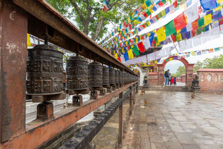 Kathmandu, Nepal - March 30, 2019: A family and prayer wheels near the buddhist monastery during an...