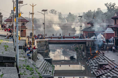 Tilanga, Kathmandu, Nepal - April 2, 2019: Three cremations are under process at the end of the afternoon of a spring sunny day at the Pashupatinath temples complexのeditorial素材