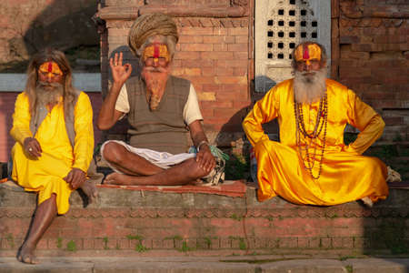 Tilanga, Kathmandu, Nepal - April 2, 2019: a group of 3 Sadhus posing for the camera, taken at the end of the afternoon of a spring sunny day at the Pashupatinath templeのeditorial素材