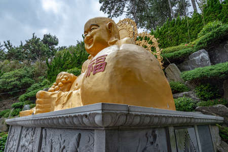 Busan, South Korea - June 9, 2019: Laughing Buddha at Yonggungsa temple on a cloudy summer afternoonのeditorial素材