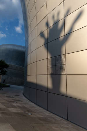 Seoul, South Korea - June 11, 2019: Shadow of a sculpture cast on a modern building wall, taken at the end of a summer afternoon at the Dongdaemun design plazaのeditorial素材