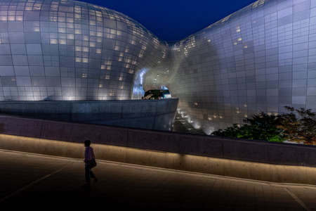 Seoul, South Korea - June 11, 2019: Passersby and detail of the Dongdaemun design plaza showing architectural lighting and building curves at nightのeditorial素材