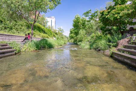 Seoul, South Korea - May 31, 2019: Two women are discussing on a bench near the clear running water of the Cheonggyecheon stream, Seoul, South Koreaのeditorial素材