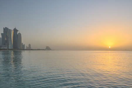 Panoramic view of Wets Bay's skyscrapers at dawn with sun rising above the sea, Doha, Qatarの写真素材