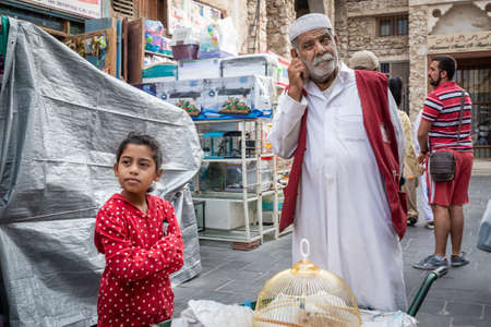 Doha, Qatar - 25 Nov 2016: A young girl costumer with her porter waiting. Taken in Souq Wakif, Doha