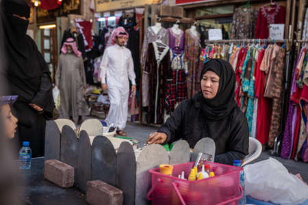 Doha, Qatar - 17 Dec 2016: An asian muslim woman is preparing crepes in the pedestrian street of the Souq Wakif, Dohaのeditorial素材