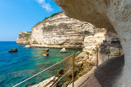 Bonifacio, Corsica, France - Sep 19, 2019: Visitors at the end pf the pathway dug out of the cliff underneath Bonifacio. Taken during a summer afternoon.のeditorial素材