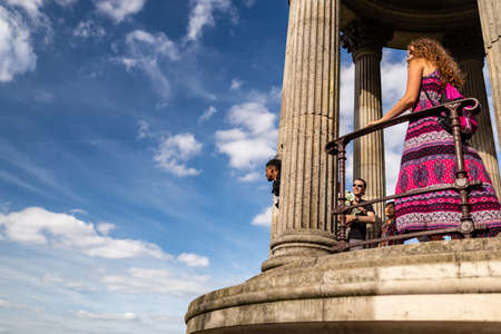 Paris, France - June 16, 2017: Visitors looking at the view from the temple of the Sybil in Buttes Chaumont Park seen through tree branches, taken on a early summer sunny afternoonのeditorial素材
