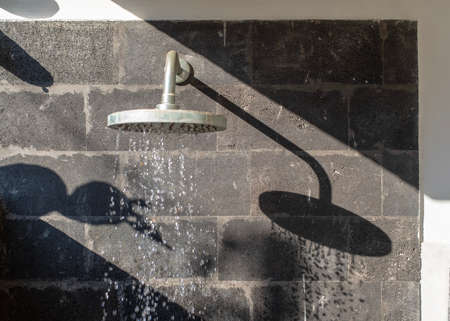 Shadow of an outside shower head on a basalt stone wall, with no people, Ubud, Bali, Indonesiaの写真素材