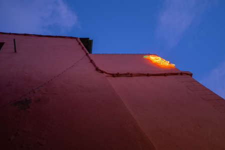 A light decoration representing Santa Claus set against a pink wall. Taken in the evening in the...