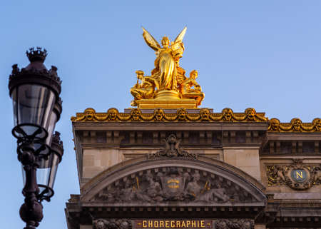 Gold sculpture on top of Paris Opera, taken on a spring morning with a Parisian standard light pole in the foreground, with no people.のeditorial素材