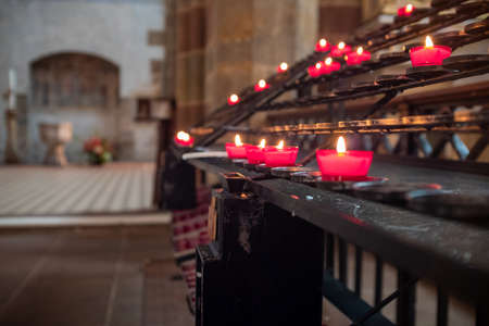 Several red candles with blurred background in St. Peter and St. Paul abbey located in Wissembourg,...