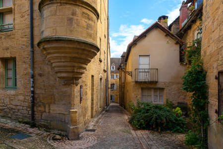 The narrow street of a beautiful french yellow stone medieval town of Sarlat-la-Caneda located in Perigord, France, taken on a sunny autumn afternoon with no peopleの写真素材