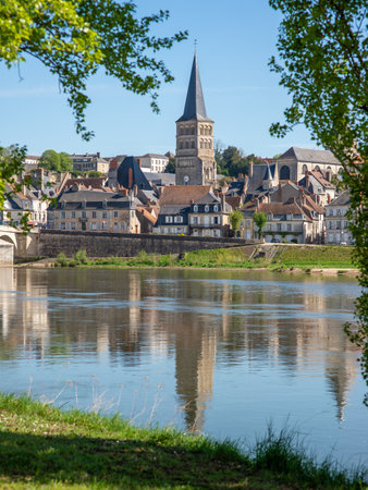 A vertical view framed with trees on the steeple of the Priory of La-CharitÃ©-sur-Loire, seen from an island across one branch of the Loire River, Burgundy, Franceの写真素材