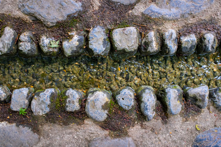 A very small water stream lined with stones. Taken on an overcast spring day.の写真素材