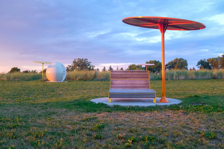 One park lounge chair and umbrella with sun setting on the side. Taken in Montreal on a sunny summer day with no peopleの写真素材